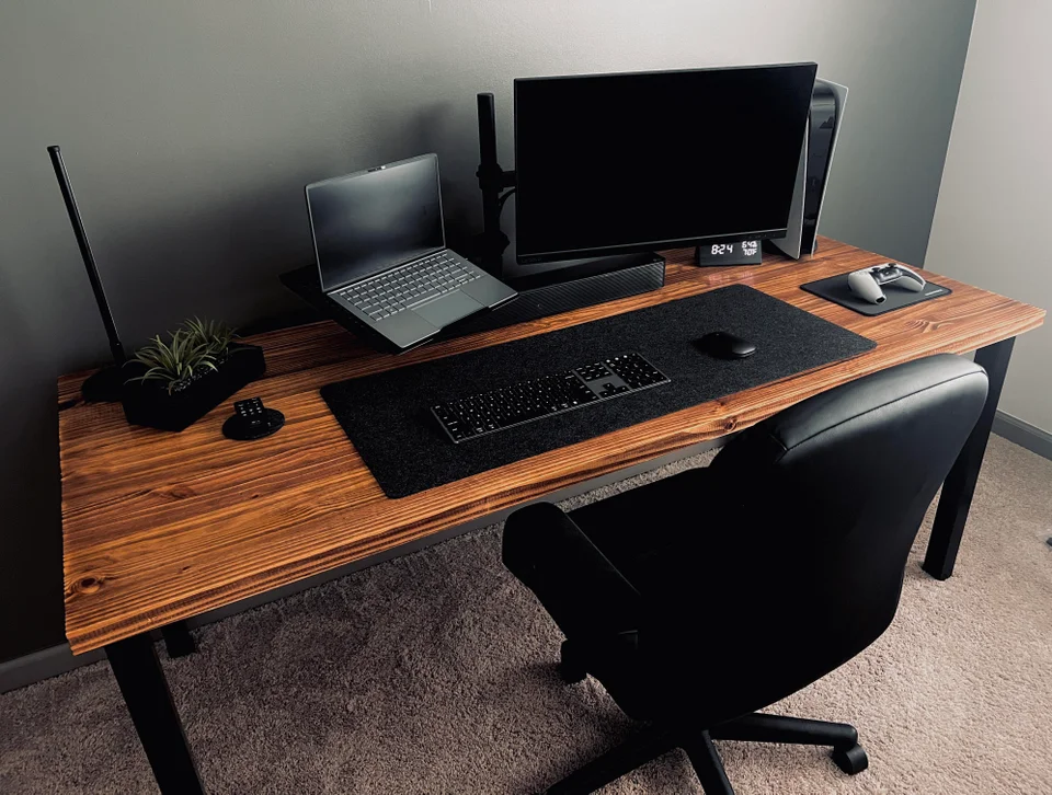 This awesome gaming setup is refined, elegant, and simple. It isn't too modern, with a touch of greenery, and a hand-polished rustic wooden desk, but the all-black accessories keep it feeling sleek. 